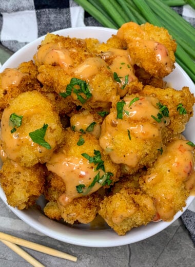 Closeup of bang bang chicken covered in sauce in a white bowl.