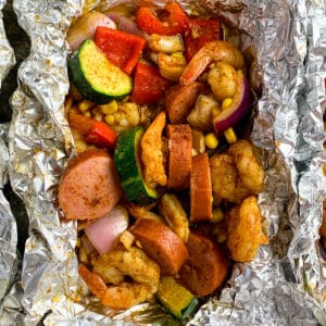 Cajun shrimp foil packets with shrimp, sausage, corn, zucchini, red onions, and cajun spices.