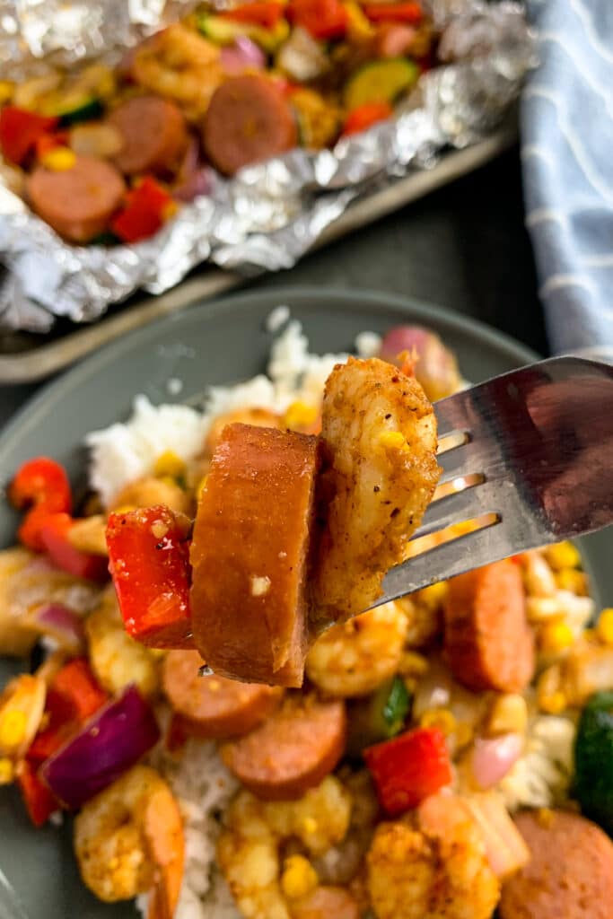 Close up of cajun shrimp and sausage on a fork.