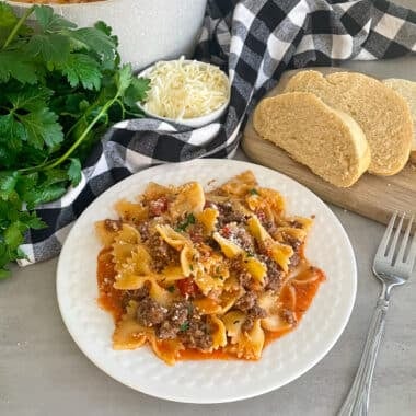 healthy one pot skillet lasagna on a white serving plate with sliced bread and parmesan cheese on the side