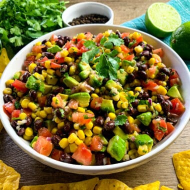 a full bowl of cowboy caviar with black beans, avocado, diced vegetables, and a zesty dressing.