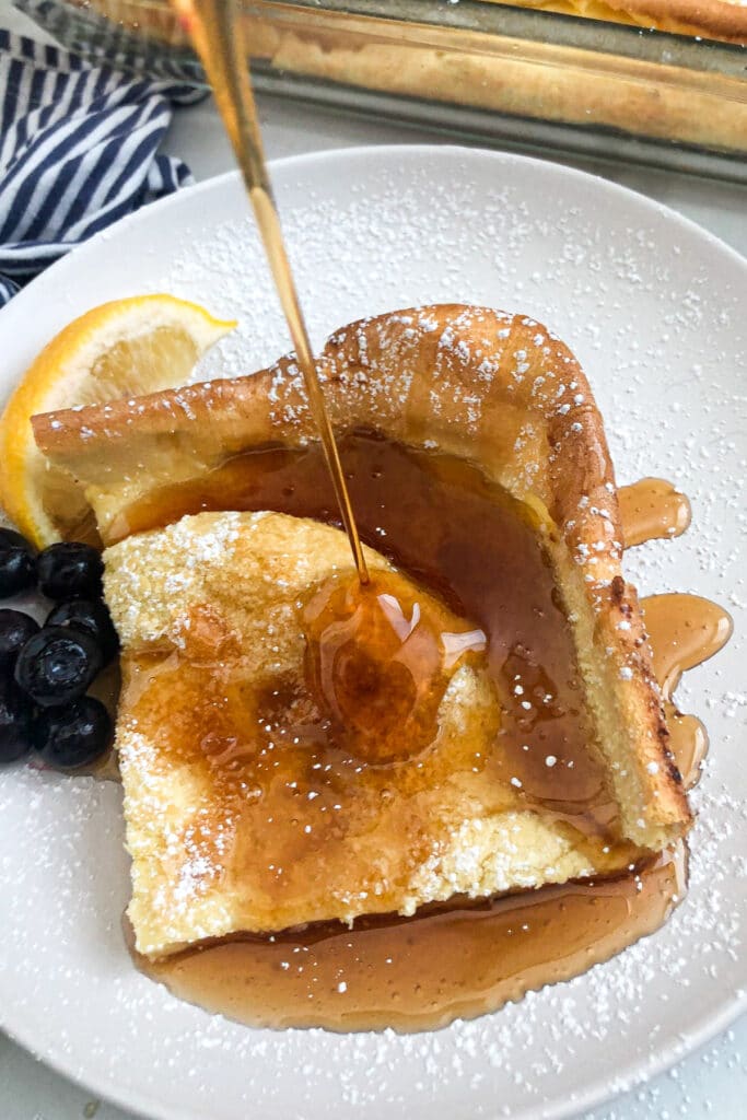 German pancakes on a serving plate with fruit and syrup on top