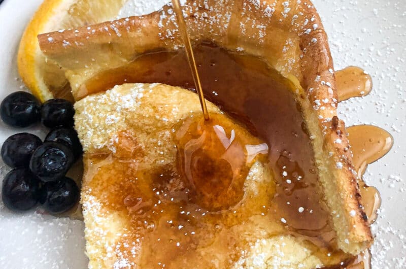 German pancakes on a serving plate with blueberries, lemon and maple syrup