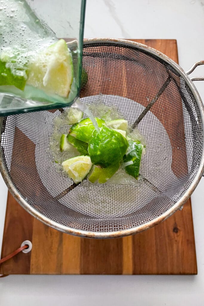 Brazilian lemonade peels going through a fine mesh strainer
