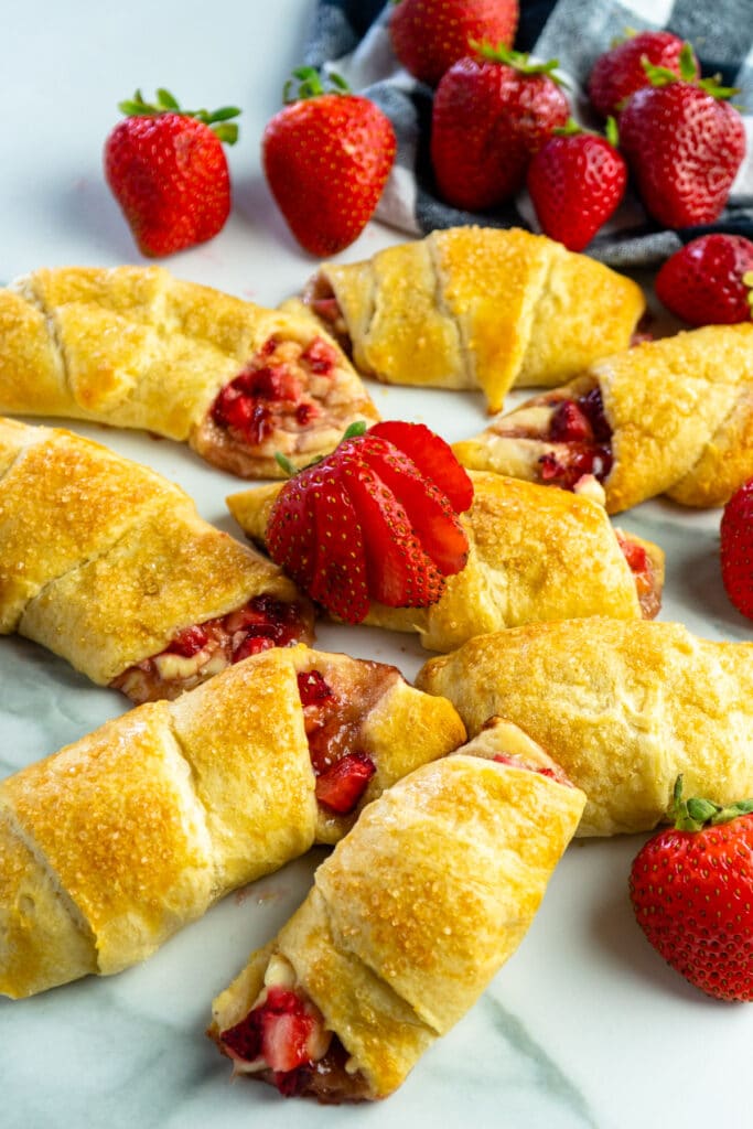 Close up of strawberry cheesecake crescent rolls garnished with fresh strawberries.