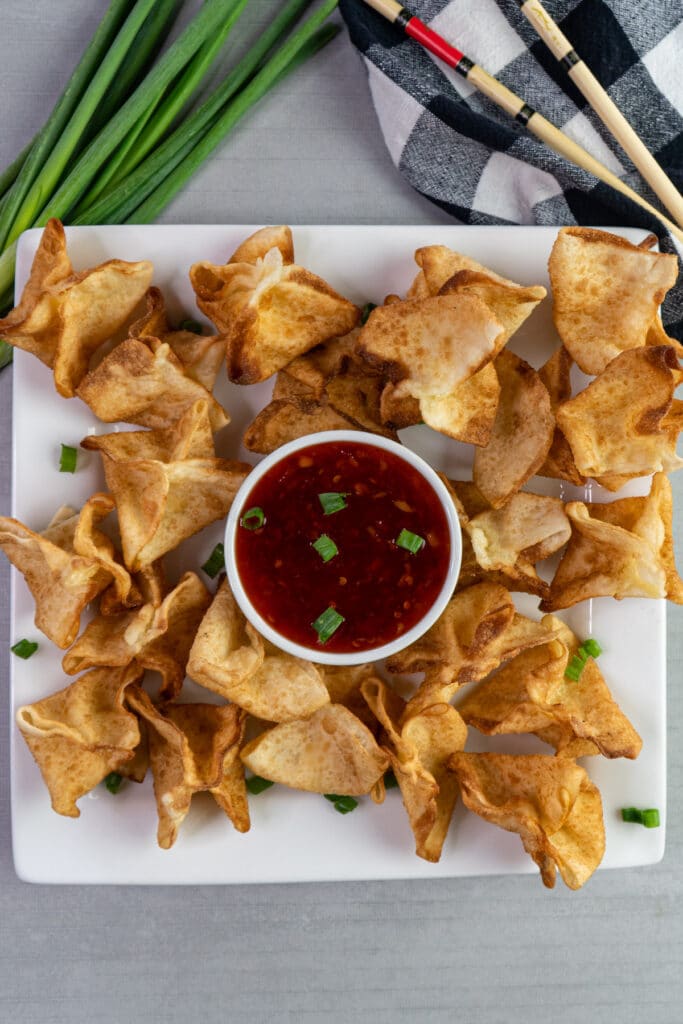 Cream cheese crab rangoons on a plate with sweet chili sauce.