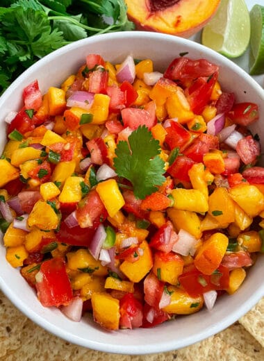 The best homemade fresh peach salsa in a serving bowl with a side or tortilla chips