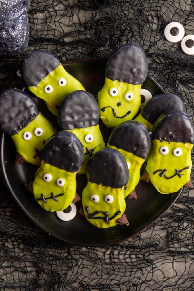 Frankenstein Nutter Butter Halloween cookies stacked up on a plate.
