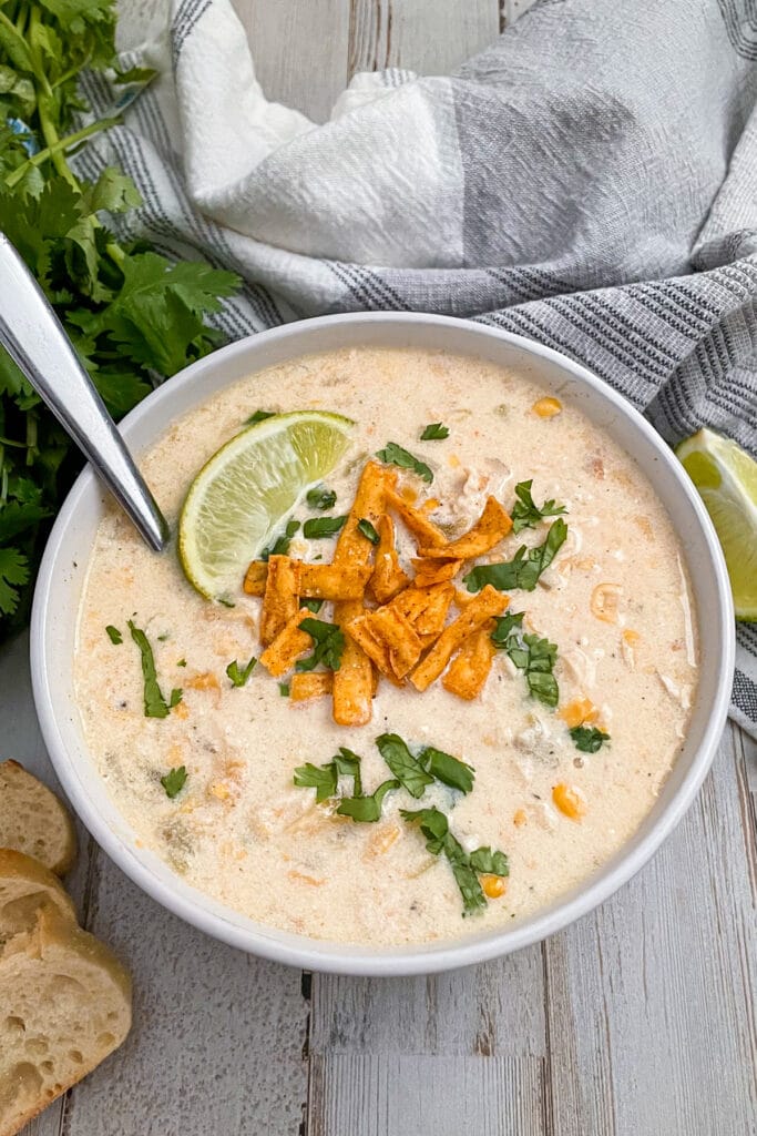 Stovetop Mexican Chicken Corn Chowder served with tortilla strips, chopped cilantro, and a lime wedge