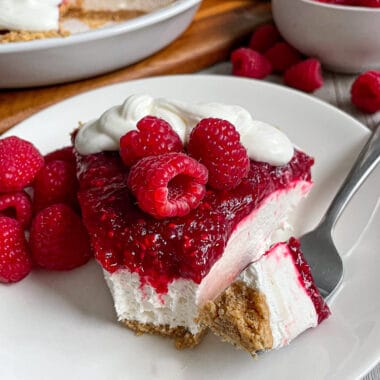 The most amazing raspberry cream pie served on a white plate with raspberries