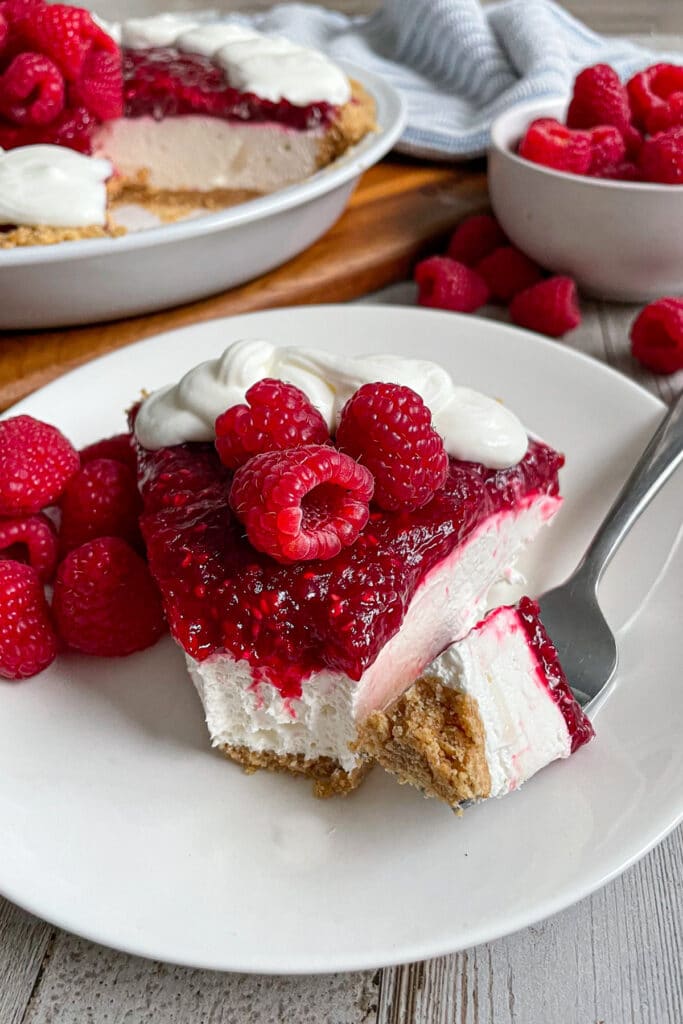The most amazing raspberry cream pie served on a white plate with raspberries