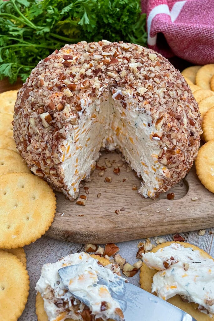 cheese ball with a wedge taken out and spread on crackers
