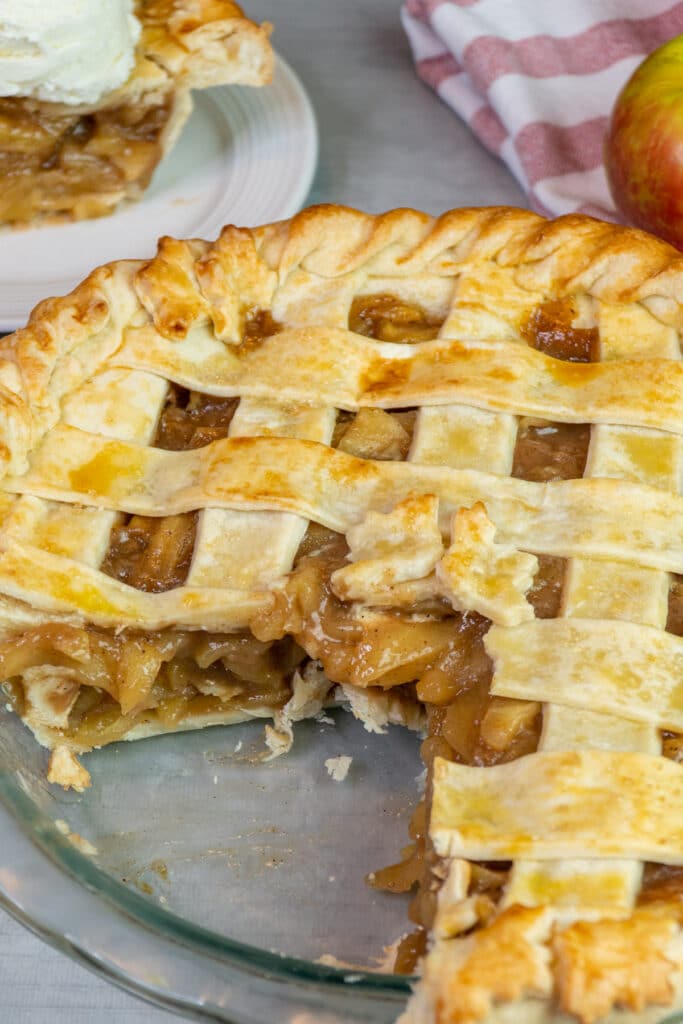 Apple pie in a baking dish with a slice taken out.