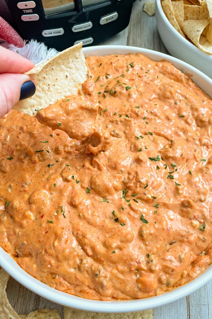 Easy crock pot cream cheese taco dip with a chip dipped into it