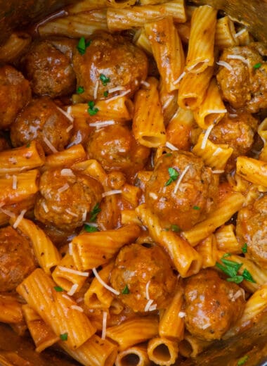 Rigatoni and meatballs in an Instant Pot garnished with Parmesan cheese and fresh parsley.