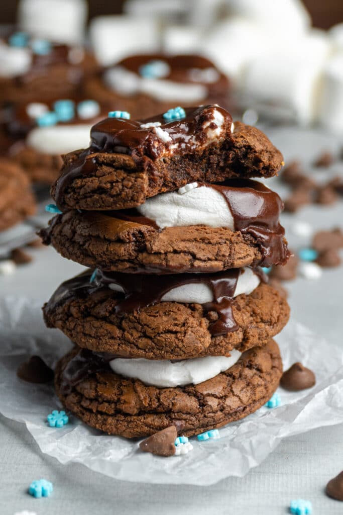 Hot cocoa cookies stacked on top of each other and one has a bite taken out of it.