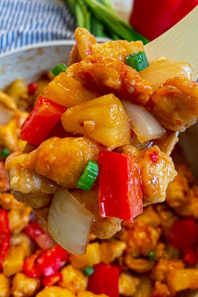 close up shot of copycat panda express sweet fire chicken on a wooden serving spoon