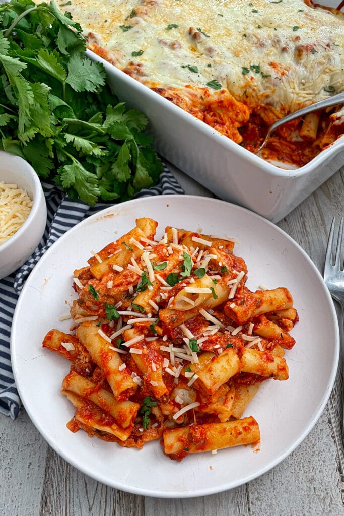 The best baked ziti served on a white plate with shredded parmesan cheese on top