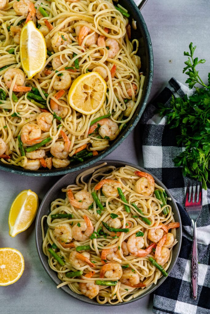 Close up of shrimp scampi with pasta and asparagus on a plate.