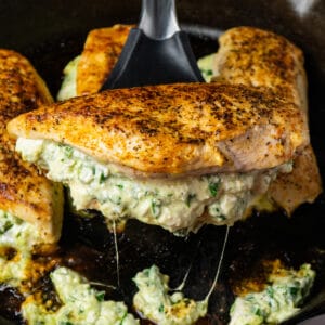 Spinach stuffed chicken breasts with cream cheese on a spatula.