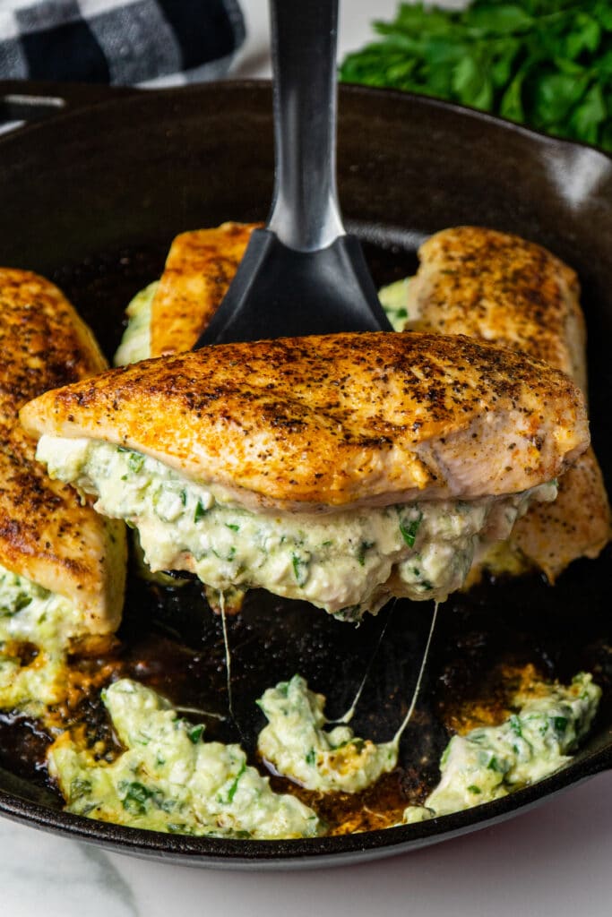 Spinach stuffed chicken breasts with cream cheese on a spatula.