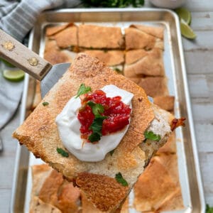 close up shot of sheet pan quesadillas topped with sour cream and salsa