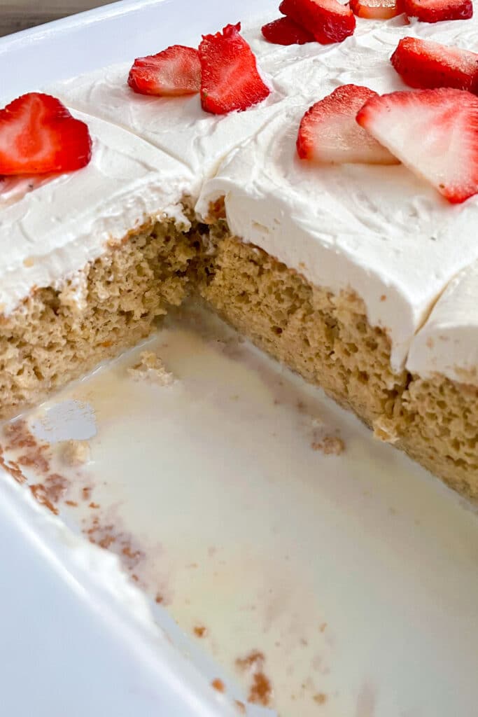 tres leches cake with a slice taken out of it for serving