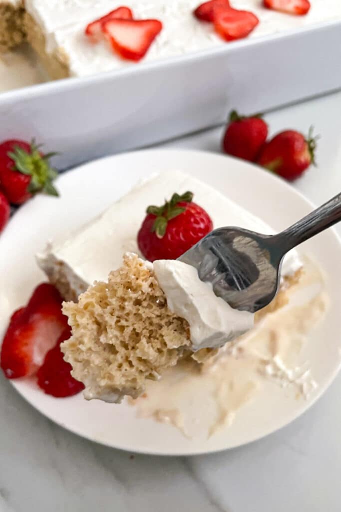 close up photo of Tres leches cake with a bite taken out of it with a fork