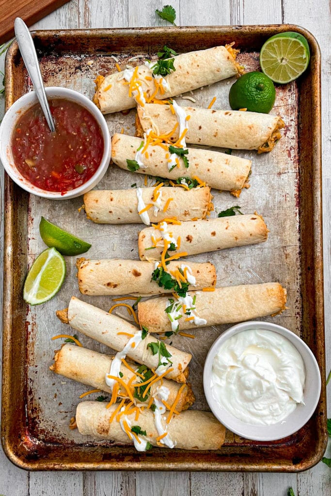 Crispy oven baked chicken taquitos served with sour cream, salsa, and lime wedges