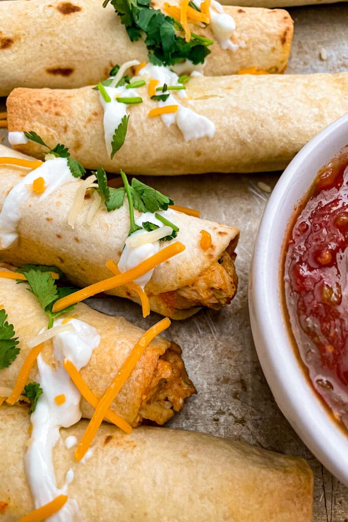Crispy oven baked chicken taquitos with shredded cheese and salsa