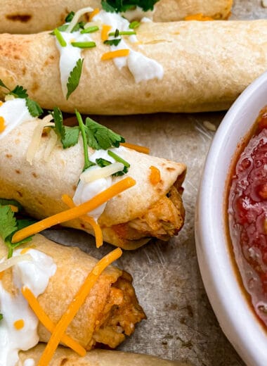 close up shot of crispy oven baked taquitos with shredded cheese and salsa