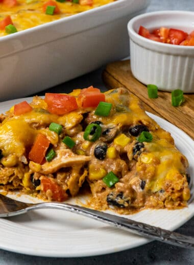 Close up of chicken taco casserole on a white plate to show off the inside.