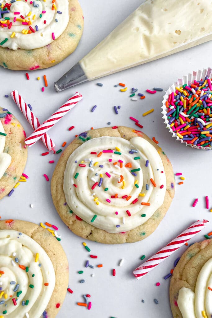 copycat crumbl birthday cake cookies with sprinkles and a piping bag with frosting