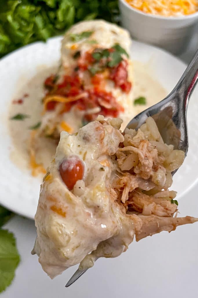 close up shot of smothered honey lime chicken burritos on a fork
