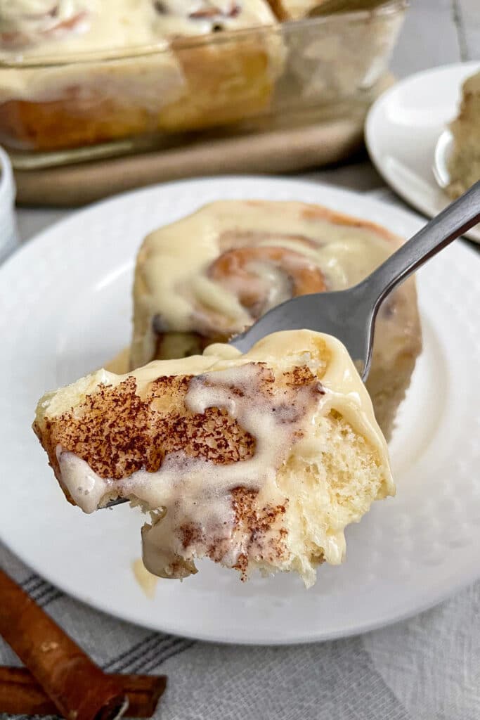 close up photo of Cinnabon cinnamon roll with a bite on a fork