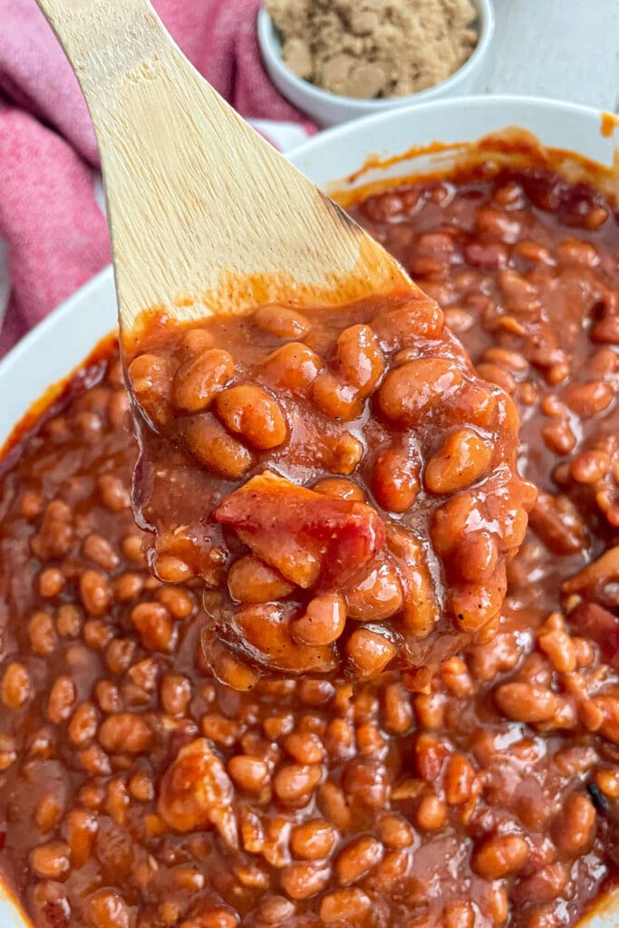 best baked beans in a casserole dish with a wooden spoon