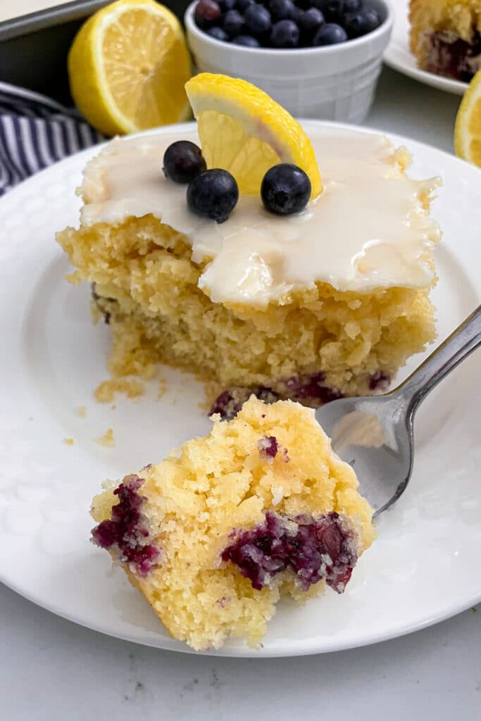 lemon blueberry cake on a serving plate with a bite taken out of it