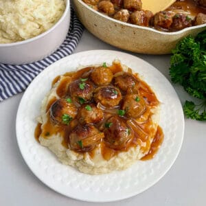 close up shot of salisbury steak meatballs on a serving plate with mashed potatoes