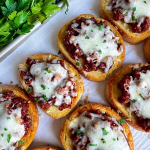 up close image of Texas toast sloppy joes on a baking sheet topped with mozzarella cheese and chopped parsley