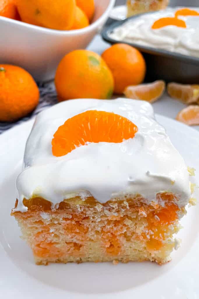 one slice of orange cream poke cake on a white serving plate