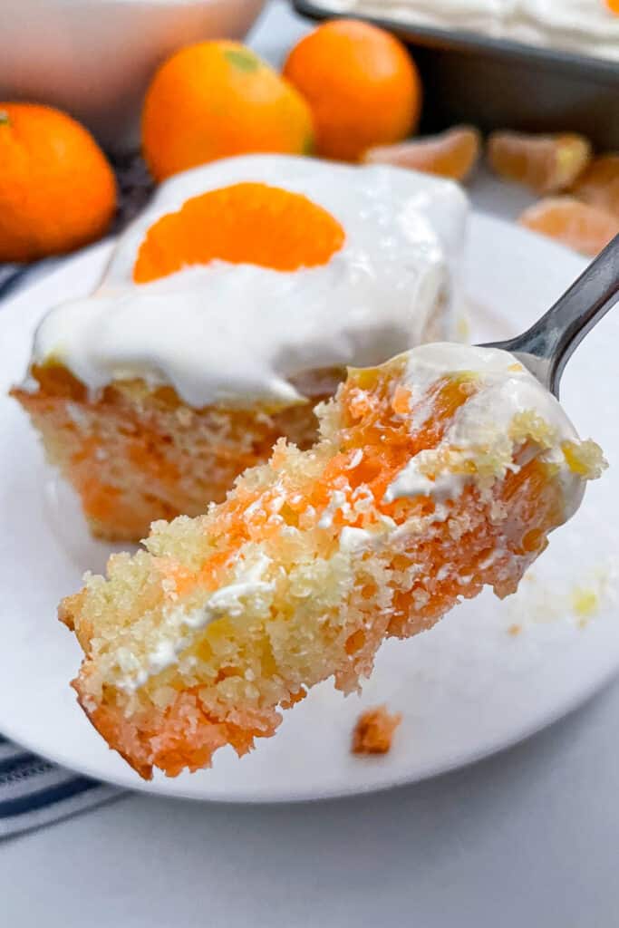 close up shot of orange poke cake on a fork