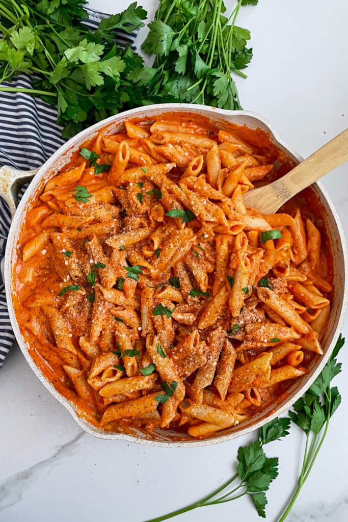 Copycat Noodles And Company Penne Rosa in a skillet topped with shredded parmesan cheese and chopped parsley