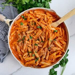 Copycat Noodles And Company Penne Rosa in a skillet topped with shredded parmesan cheese and chopped parsley
