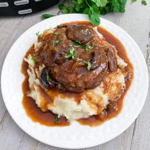 Slow Cooker Salisbury Steak served over mashed potatoes and drizzled with gravy