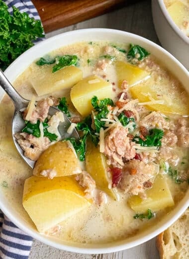 Best Olive Garden Zuppa Toscana Soup in a white serving bowl topped with bacon bits and fresh parsley.