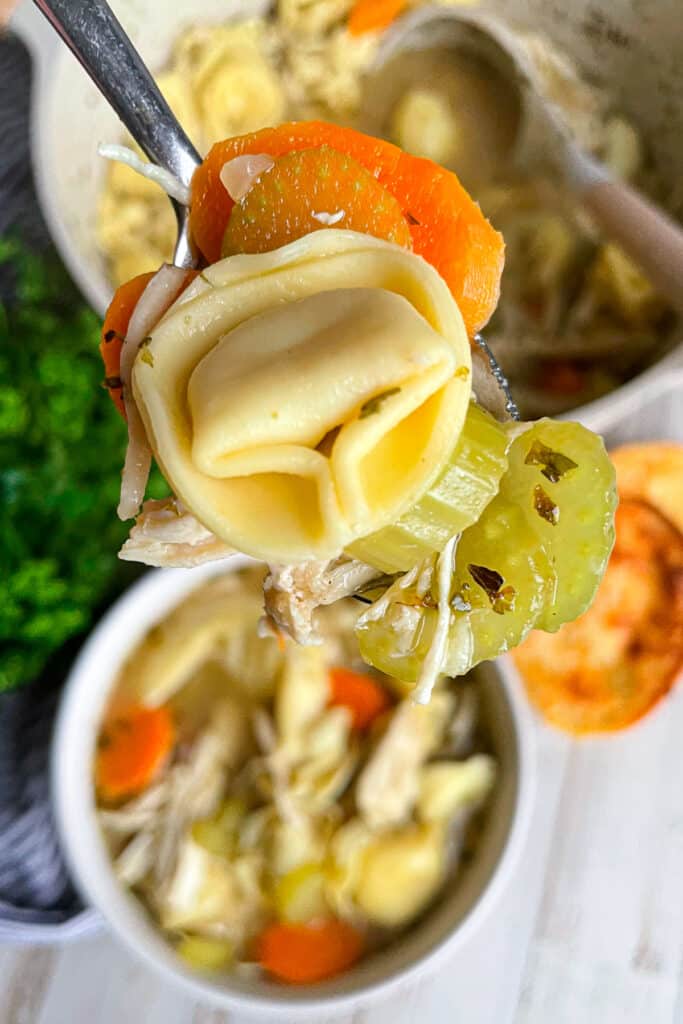 close up shot of chicken tortellini soup on a spoon for serving.