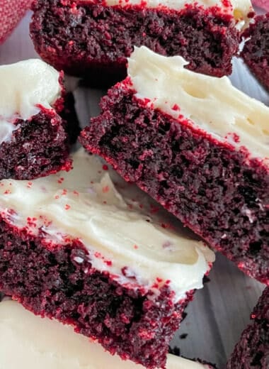 Red Velvet brownies with cream cheese frosting stacked beside eachother
