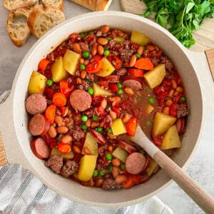 Easy Cowboy Stew recipe served in a large pot with sliced bread in the upper left hand corner