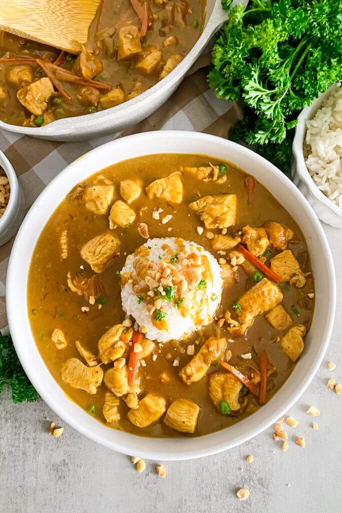 bang bang chicken recipe in a white serving bowl with a scoop of white rice in the middle garnsihed with peanuts and fresh parsley