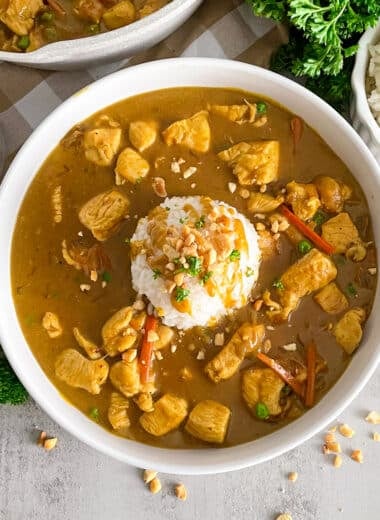 bang bang chicken recipe in a white serving bowl with a scoop of white rice in the middle garnsihed with peanuts and fresh parsley